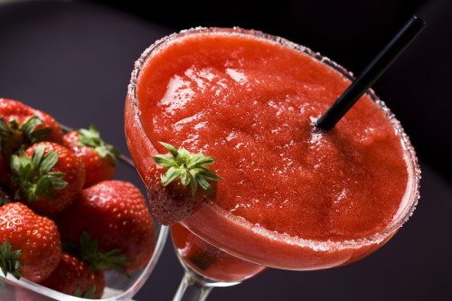 Daiquiri cocktail with strawberries over black background