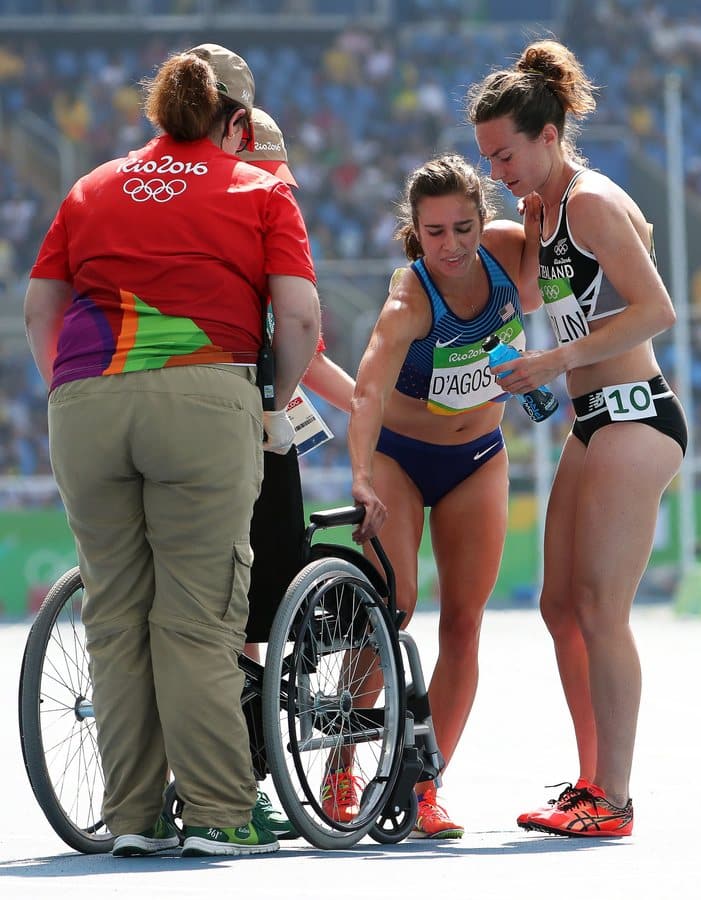 epa05491366 Abbey D'Agostino (C) of the USA is helped by Nikki Hamblin (R) of New Zealand after both fell during the women's 5000m heats of the Rio 2016 Olympic Games Athletics, Track and Field events at the Olympic Stadium in Rio de Janeiro, Brazil, 16 August 2016. EPA/SRDJAN SUKI
