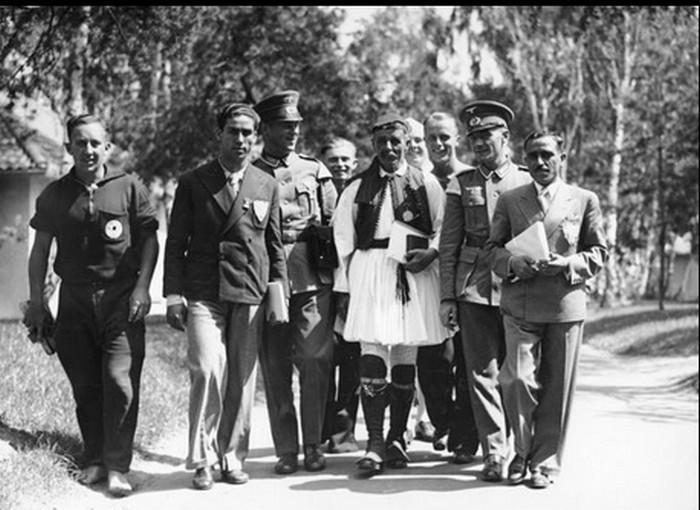 Μέλη της ελληνικής αποστολής και Γερμανοί αστυνομικοί συνοδεύουν τον Σπύρο λούη στο Ολυμπιακό Χωριό του Βερολίνου.